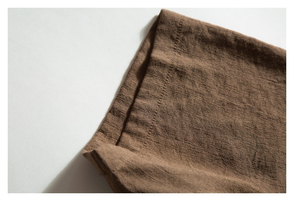 Close-up of brown garment fabric with a folded, stitched edge.
