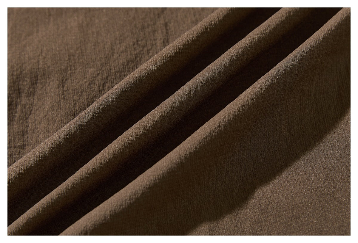 Macro view of brown fabric draped in folds, showing its fine textured surface.