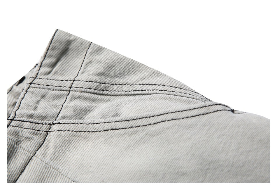 Close-up of gray washed denim shorts showing parallel stitched seams and a fabric panel.