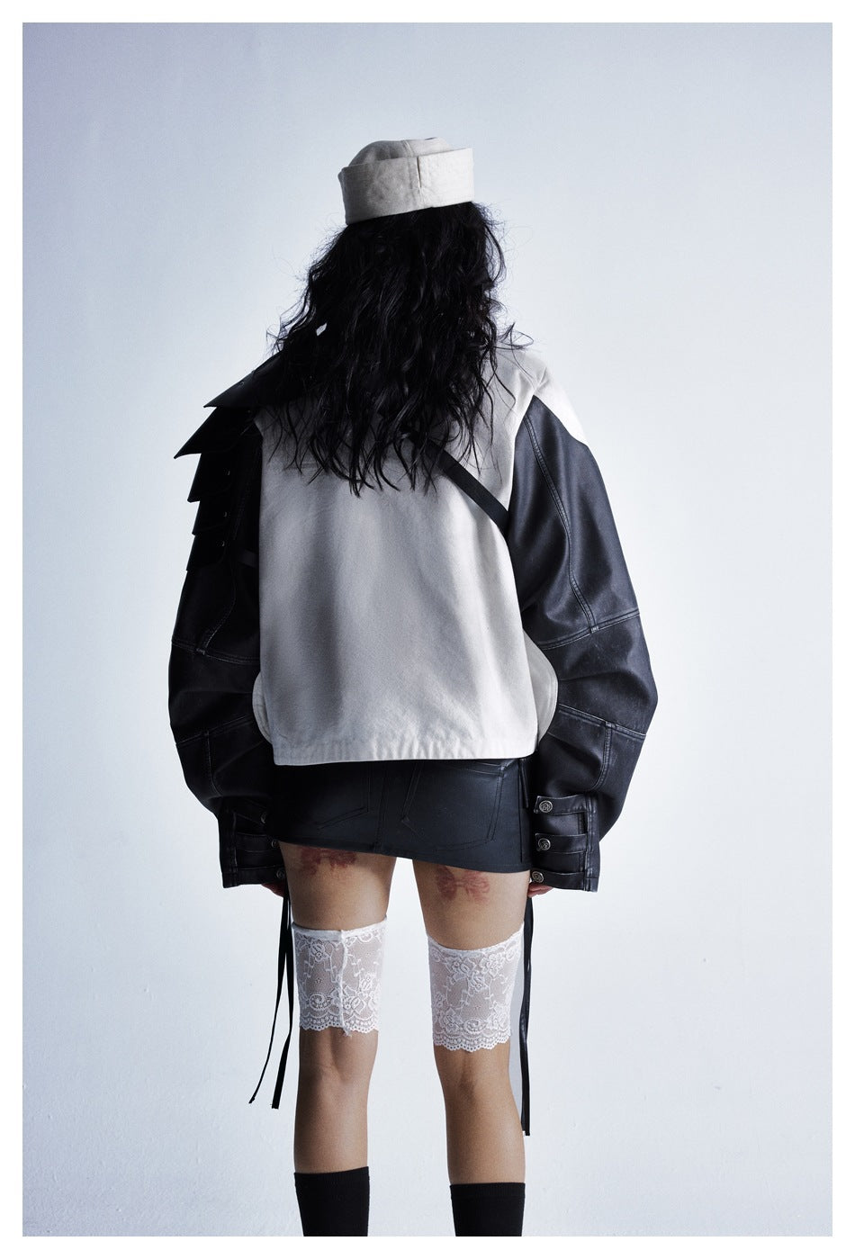 Rear view of a model wearing the off-white jacket with black sleeves and layered shoulder panels.