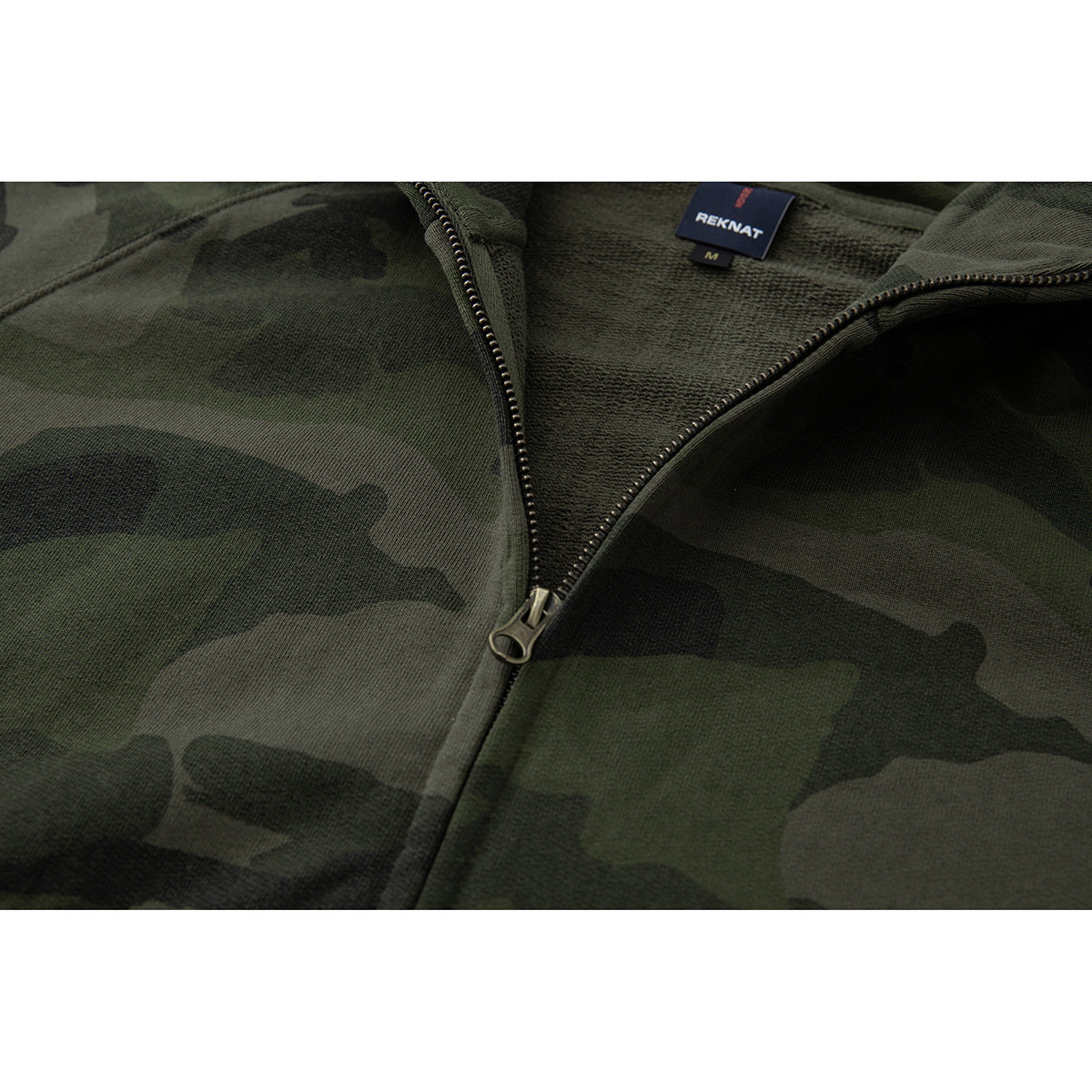 Close-up of the dark green camouflage hoodie’s open zipper, inner hood fabric, and sewn neck label.