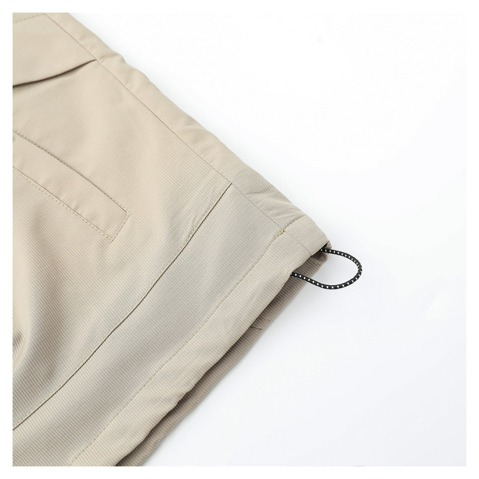 Close-up of a beige jacket hem with a black drawcord and stitched panel seam.