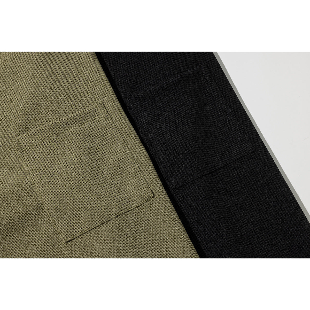Close-up of square chest pockets on olive and black textured T-shirts.
