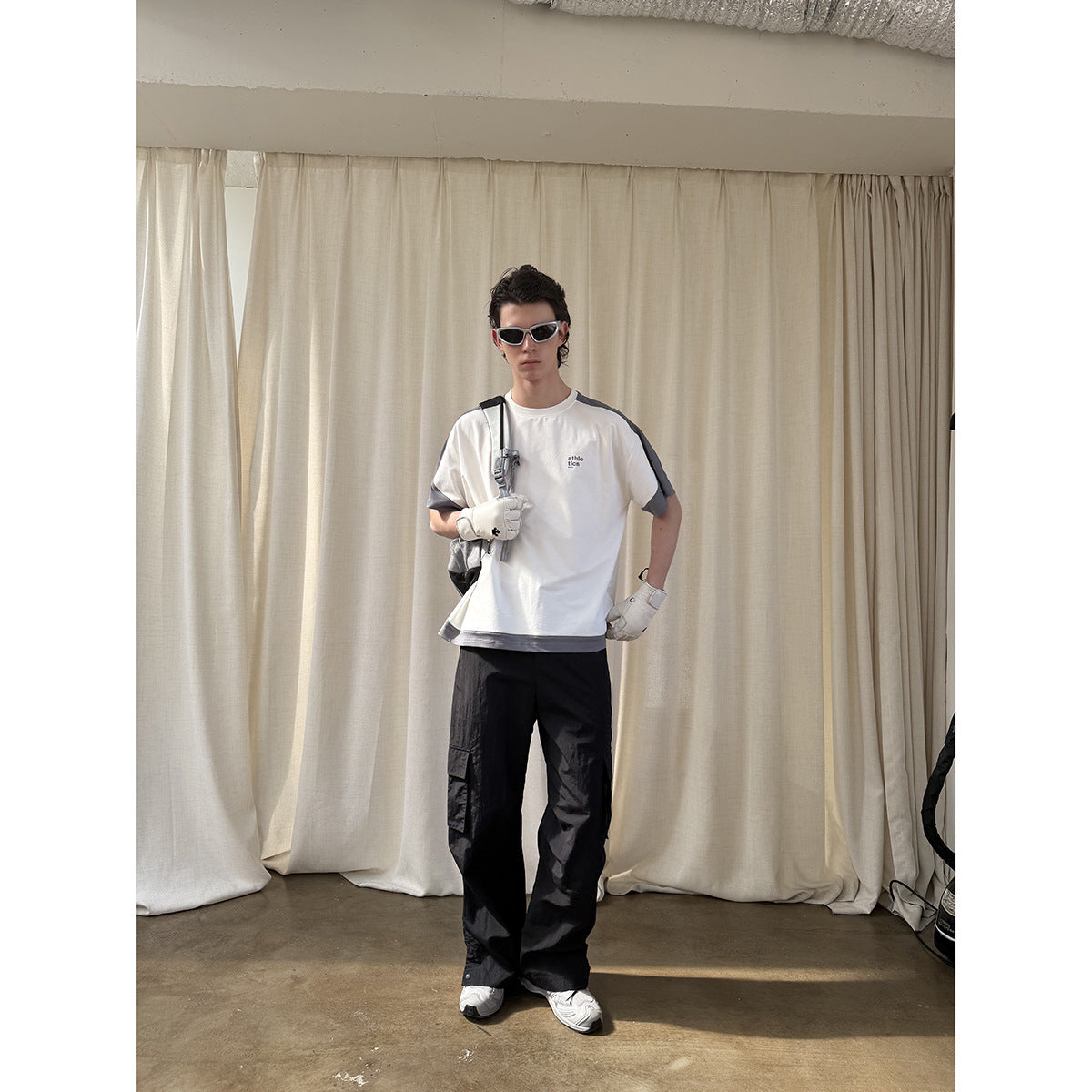 Model wearing a white T-shirt with gray contrast sleeves and hem, paired with black cargo pants.