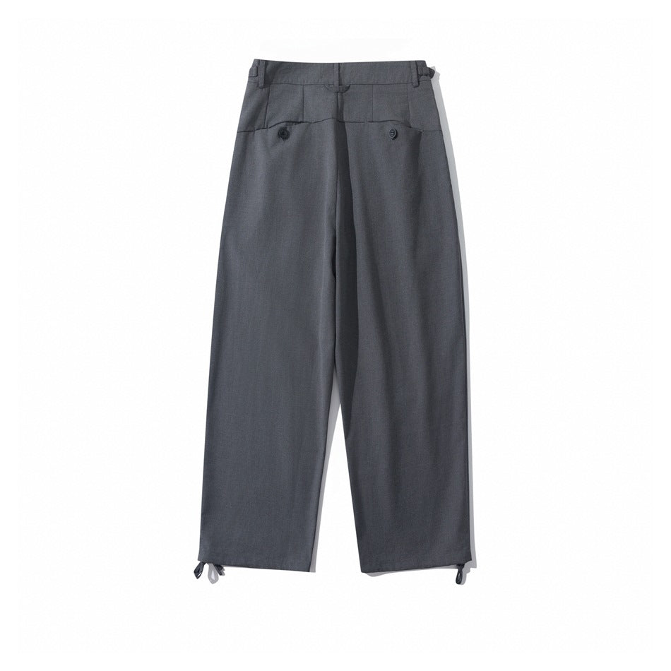 Back view of charcoal gray wide-leg trousers with a high waistband, two buttoned pockets, and hem ties.