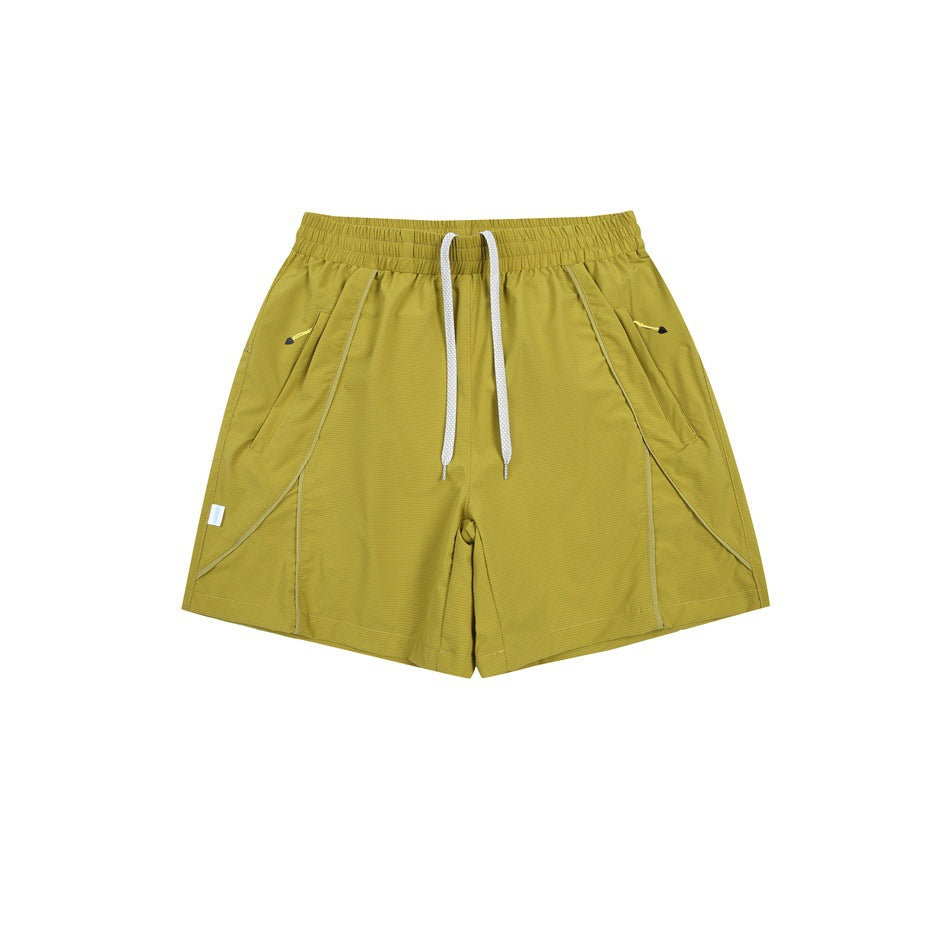 Olive green athletic shorts flat lay with white drawstring, elastic waist and diagonal side pockets with yellow zip pulls