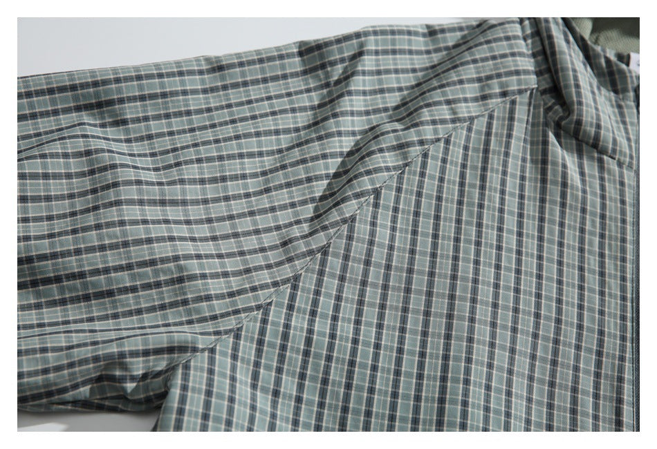 Close-up of the gray-green plaid jacket sleeve and underarm seam.