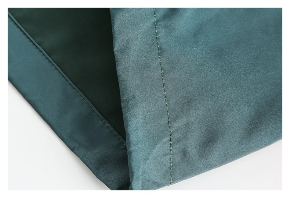 Close-up of stitched seams on teal garment fabric.