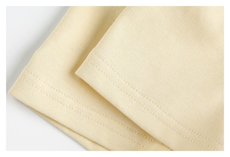 Close-up of the cream garment's sleeve cuffs and parallel rows of stitching.