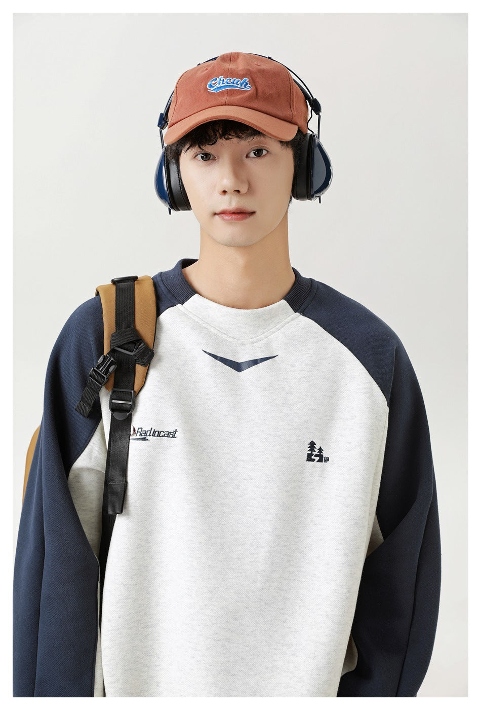 Close view of a model wearing a cream sweatshirt with navy raglan sleeves and a small chest graphic.