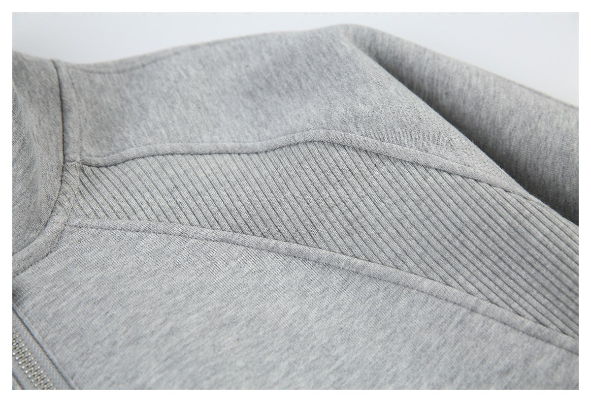 Close-up of a ribbed shoulder panel and stitched seams on the light gray sweatshirt.