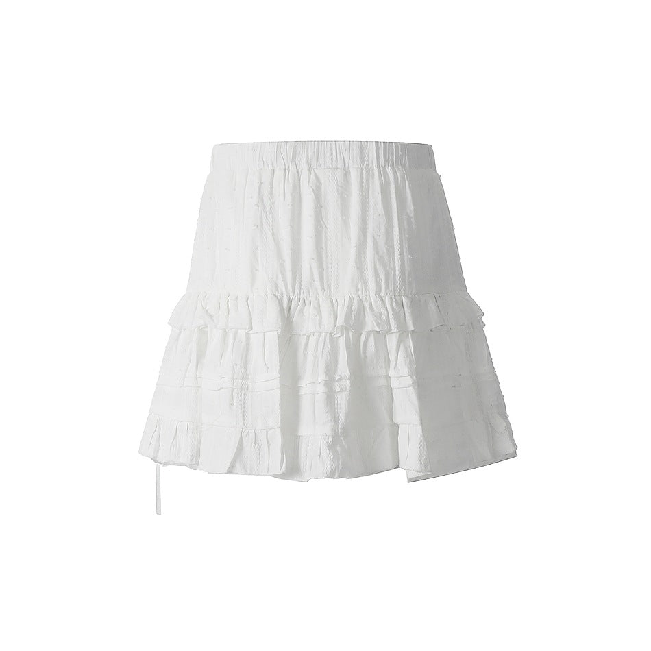 White tiered ruffle mini skirt with elastic waistband and textured dot fabric, back view on a plain white background