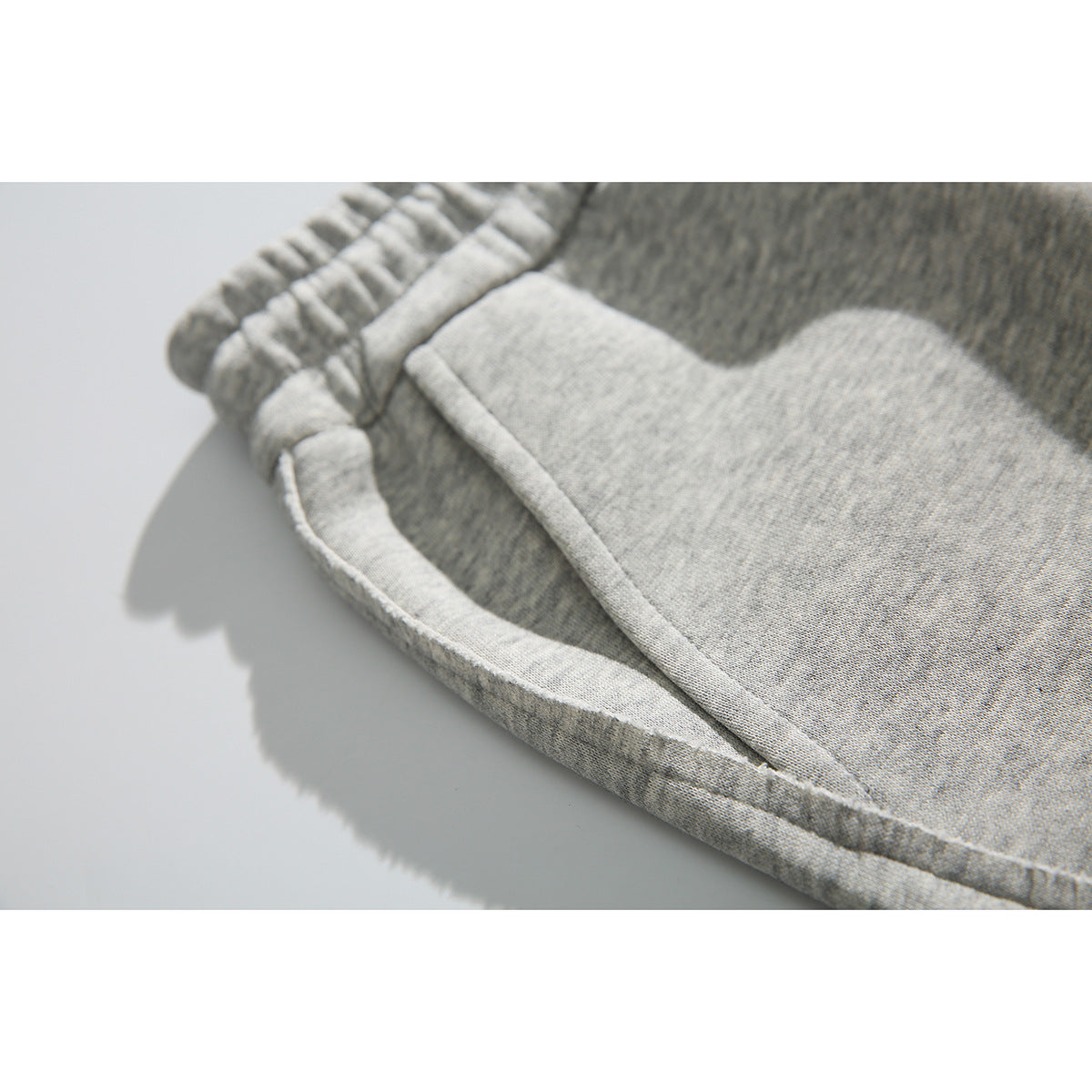 Close-up of a heather-gray sweatpants side pocket and stitching.