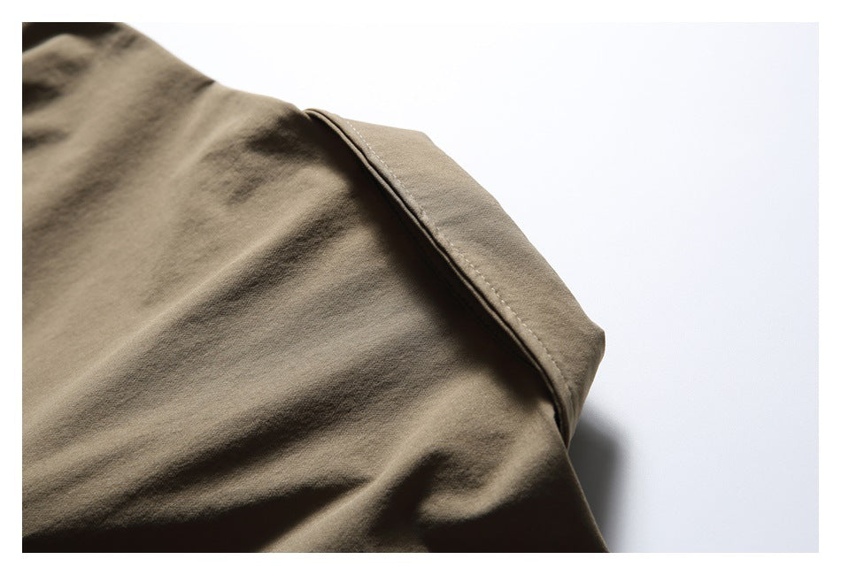 Close-up of taupe-brown garment fabric with a folded edge and visible stitching.