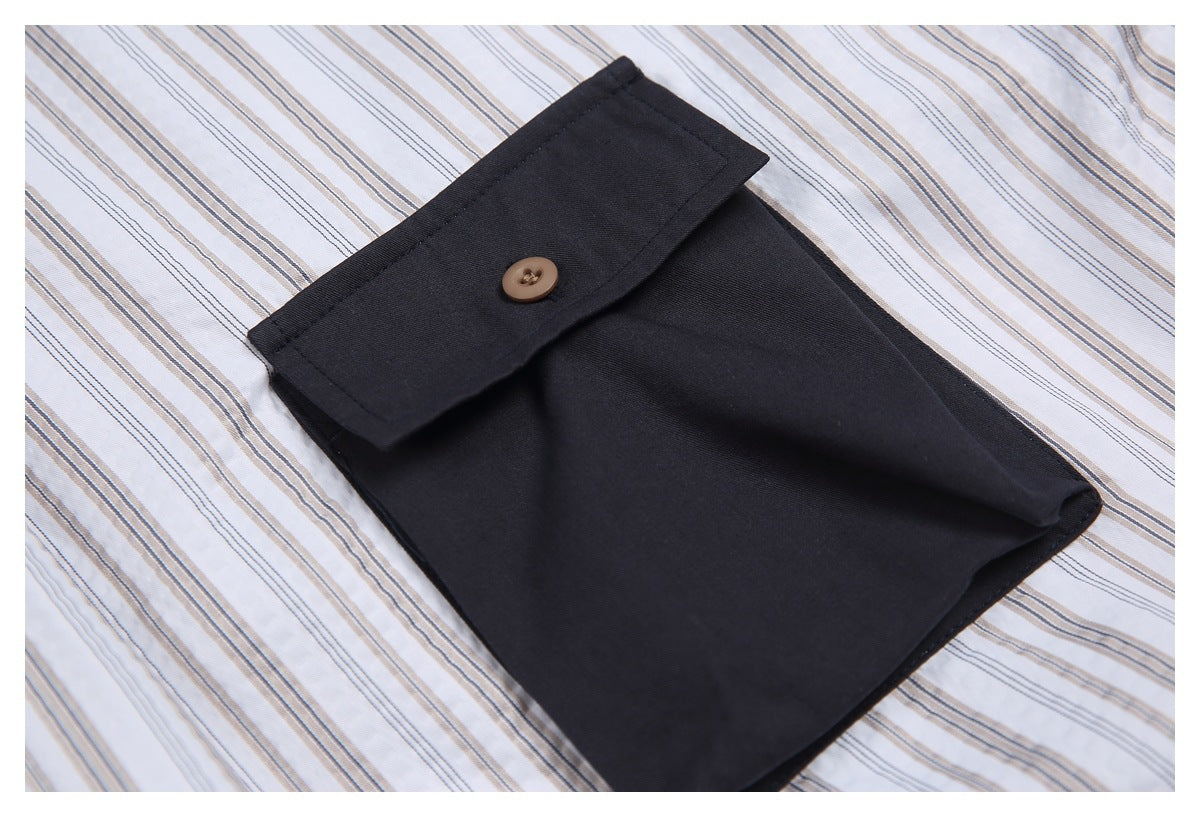 Close-up of a dark navy buttoned fabric flap against white fabric with fine gray and tan stripes.