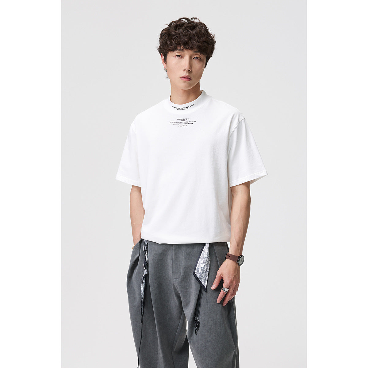 Model wearing a white short-sleeve T-shirt with a high crew neck and small chest text, shown from the front.