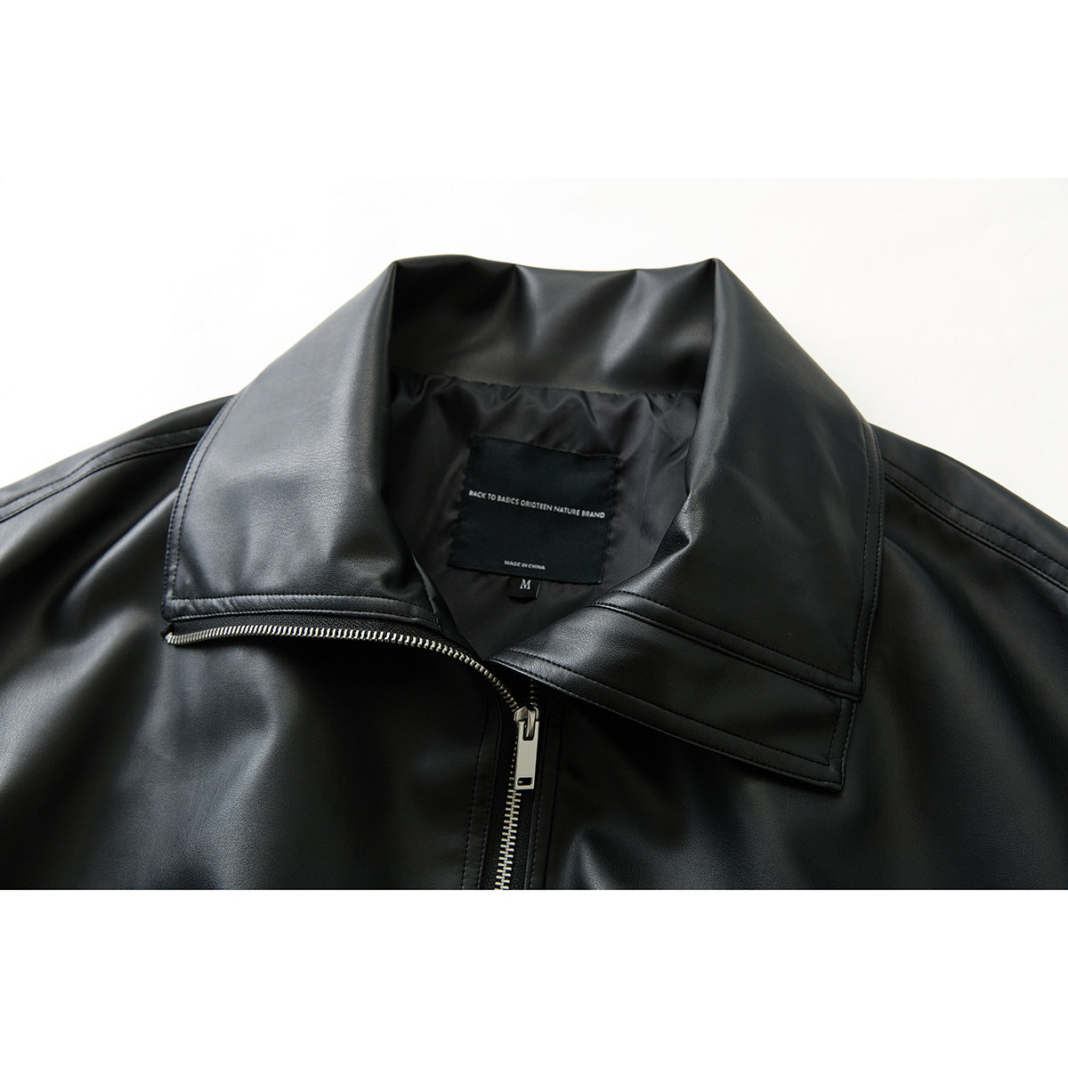 Close-up of a black jacket's wide collar, silver zipper, and inner English-language label.