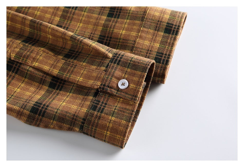 Close-up of a brown, mustard, and dark green plaid shirt cuff with a white button.
