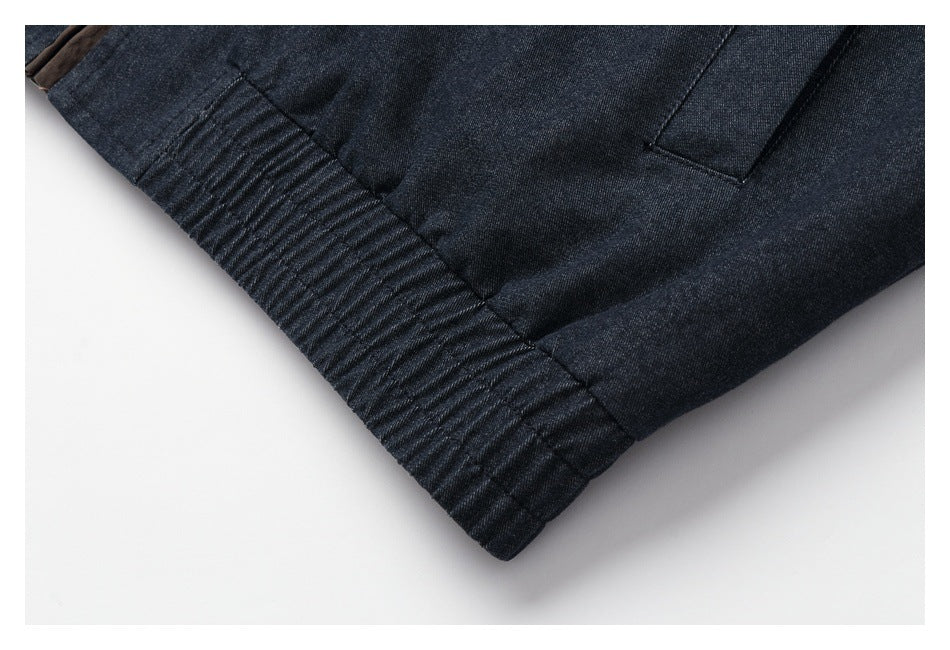 Close-up of the dark jacket's gathered ribbed hem and a rectangular pocket opening.