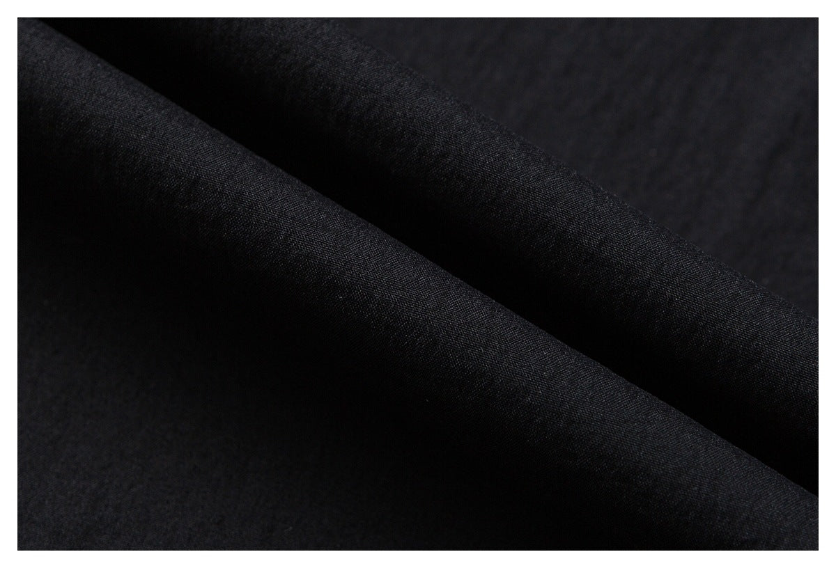 Close-up of black fabric draped in diagonal folds, showing its fine surface texture.