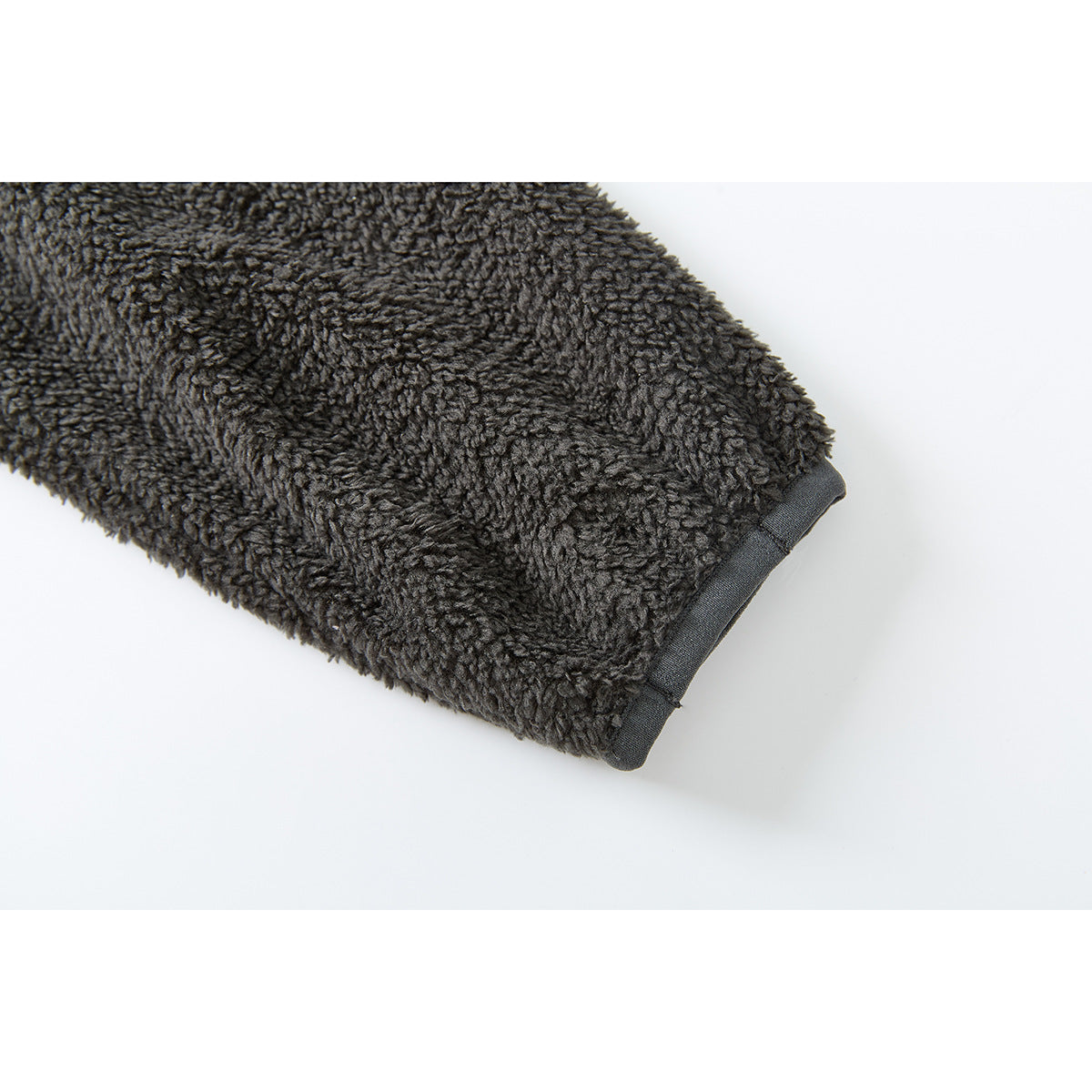 Close-up of a charcoal fleece sleeve ending in a smooth dark cuff binding.