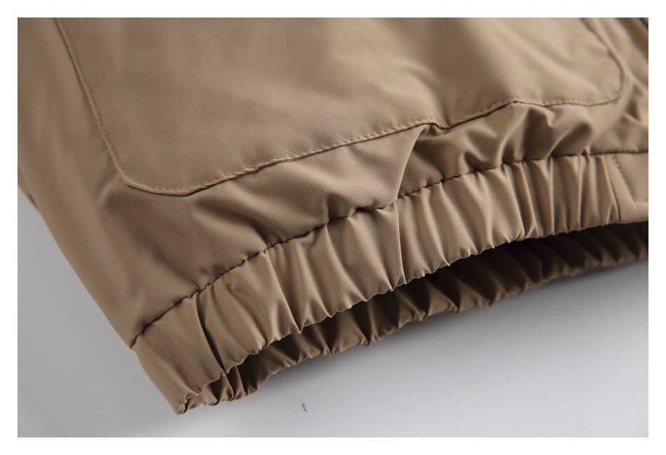 Close-up of the tan jacket's gathered elastic hem and lower pocket stitching.