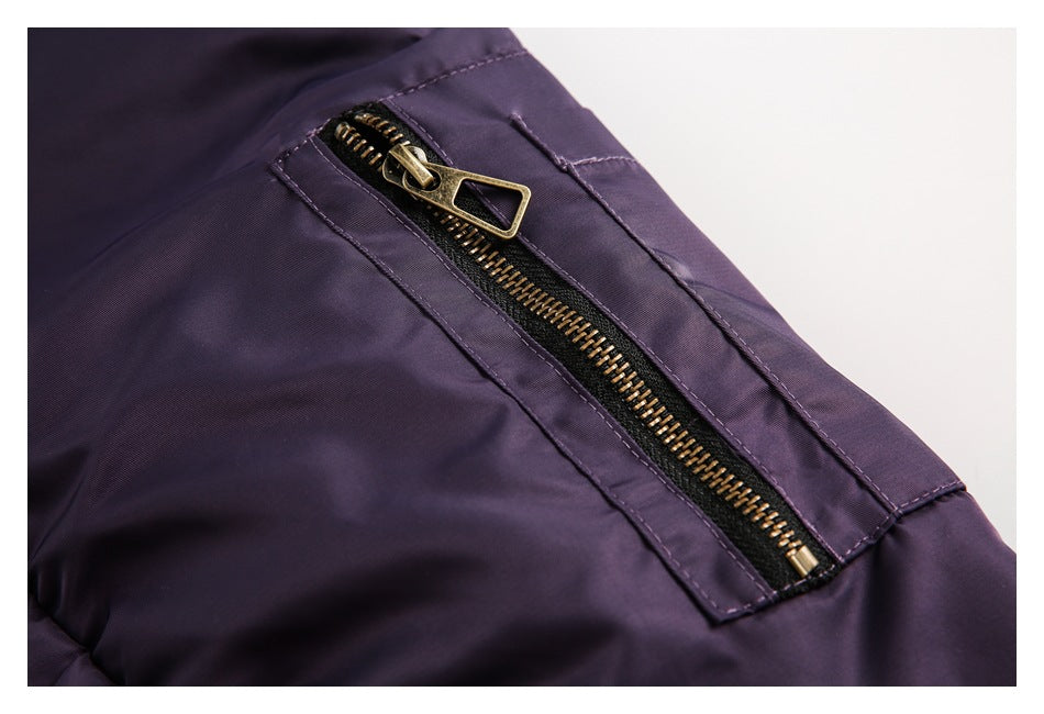 Close-up of a dark purple jacket's angled pocket with a brass-tone zipper.