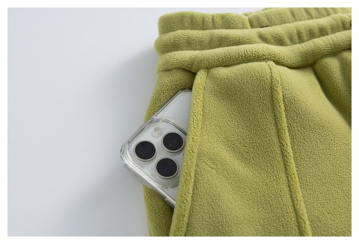 Close-up of an olive-green fleece pants pocket with a smartphone partly tucked inside.