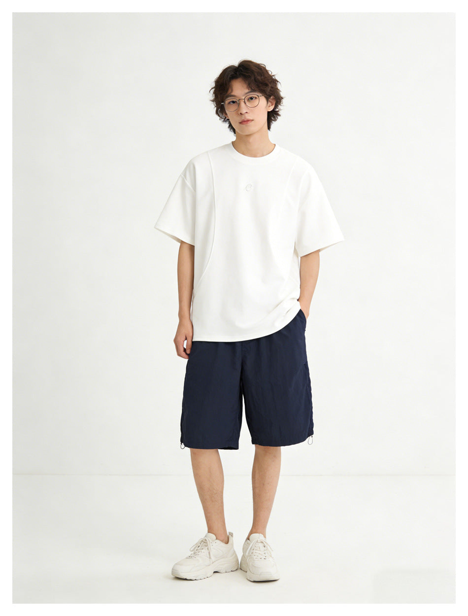 Model wearing a white oversized short-sleeve T-shirt with navy shorts and white sneakers, front view