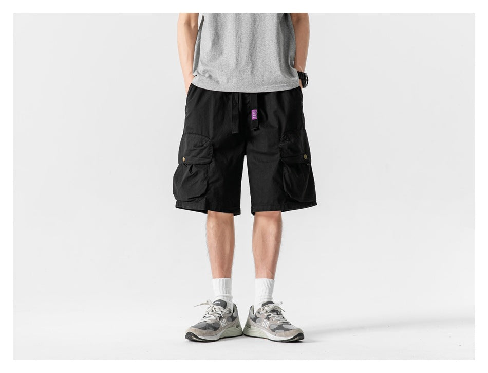 Front view of a model wearing black cargo shorts with large buttoned flap pockets.