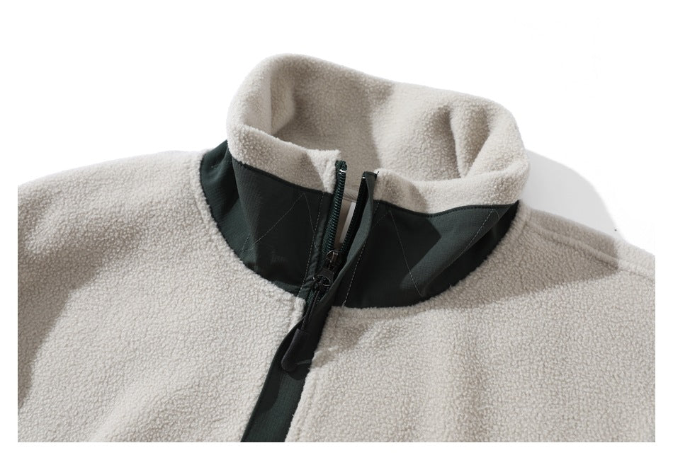 Close-up of the cream fleece pullover's high collar, dark green panel and front zipper.