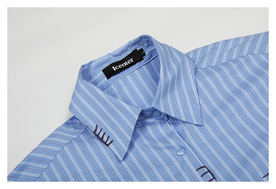 Close-up of a blue-and-white striped shirt collar, buttons, and dark decorative stitching.