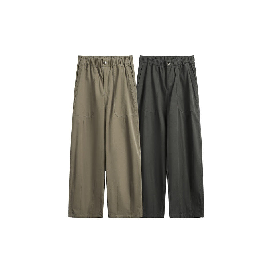 Two pairs of wide-leg trousers shown from the front in muted olive and dark charcoal, with elastic waists and patch pockets.