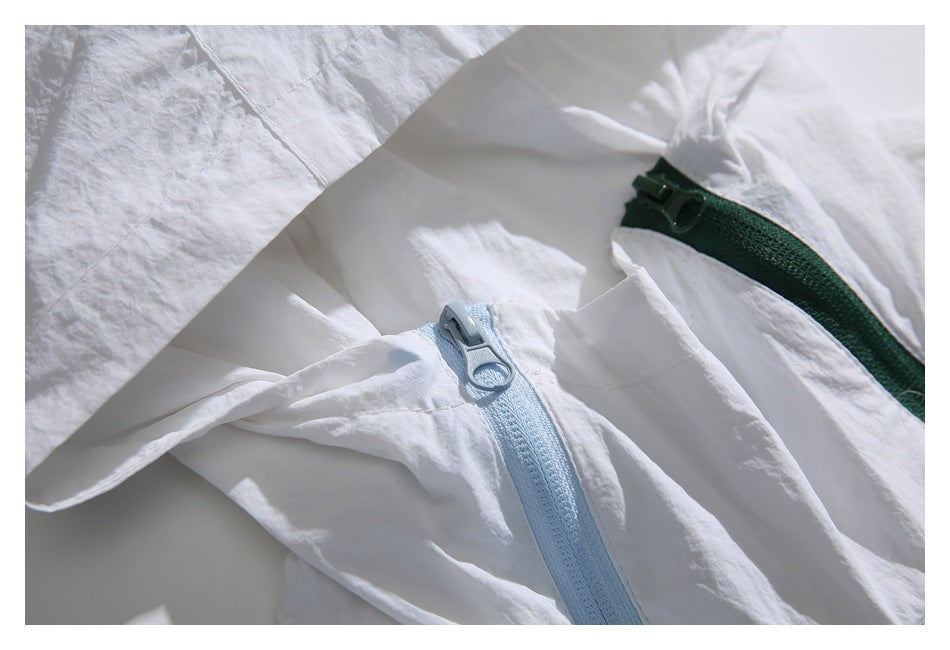 Close-up of the white jacket with pale blue and dark green zippers and ring-shaped pulls.