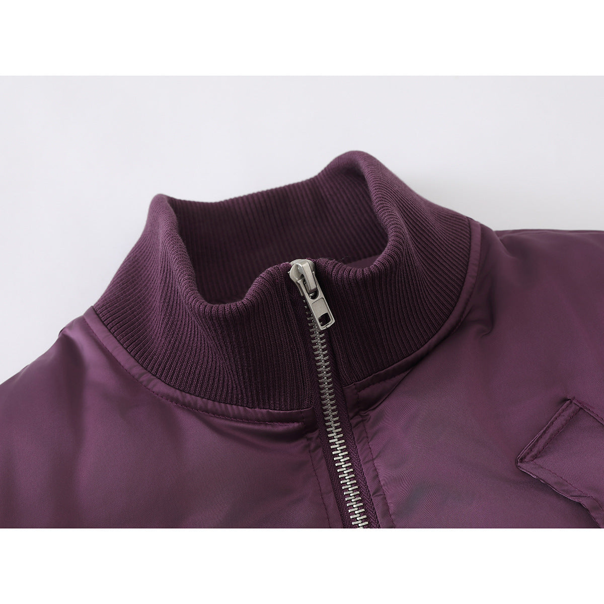Close-up of a plum jacket’s ribbed stand collar and silver front zipper.