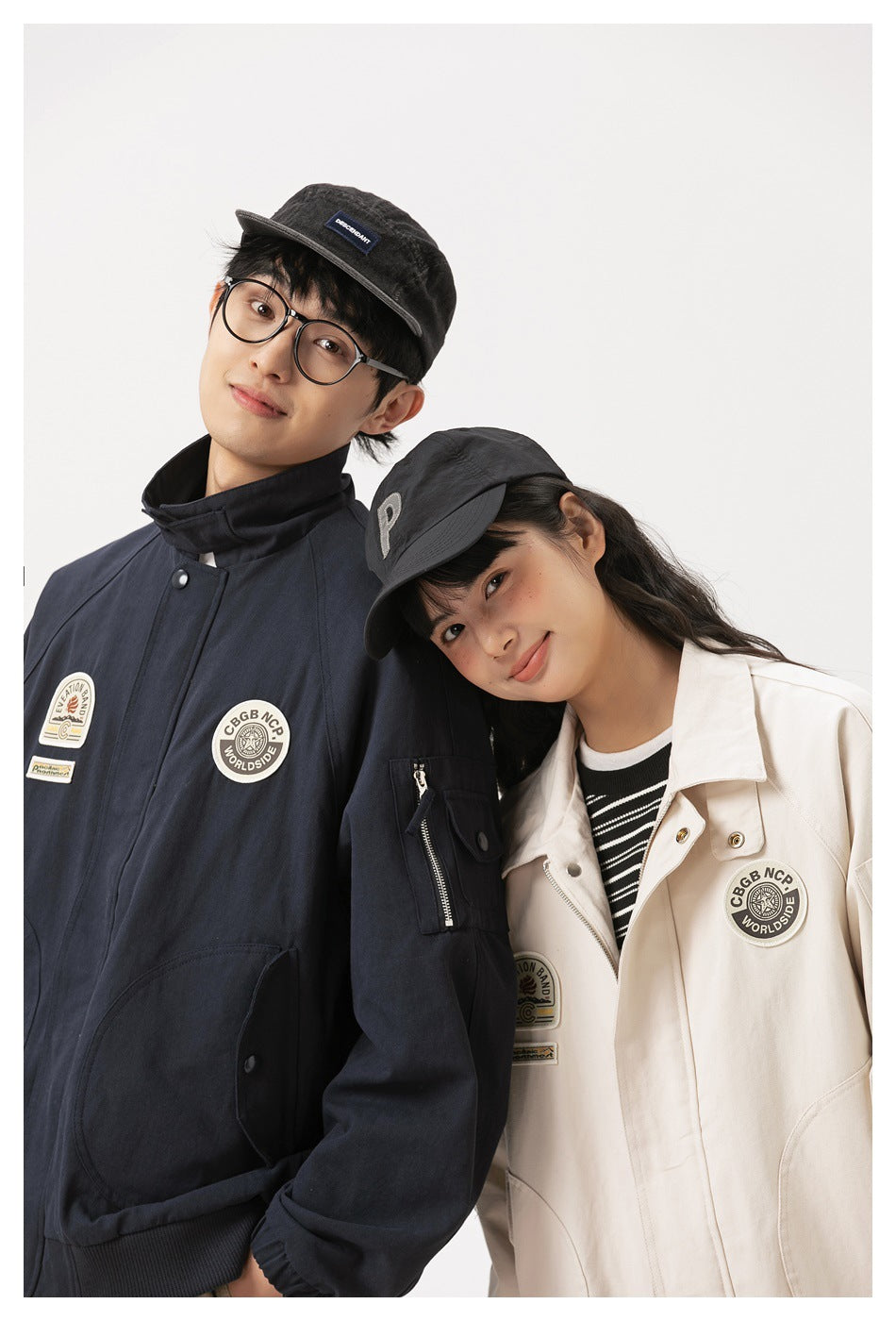 Close view of two models wearing navy and ivory jackets with high collars, patches, and utility pockets.