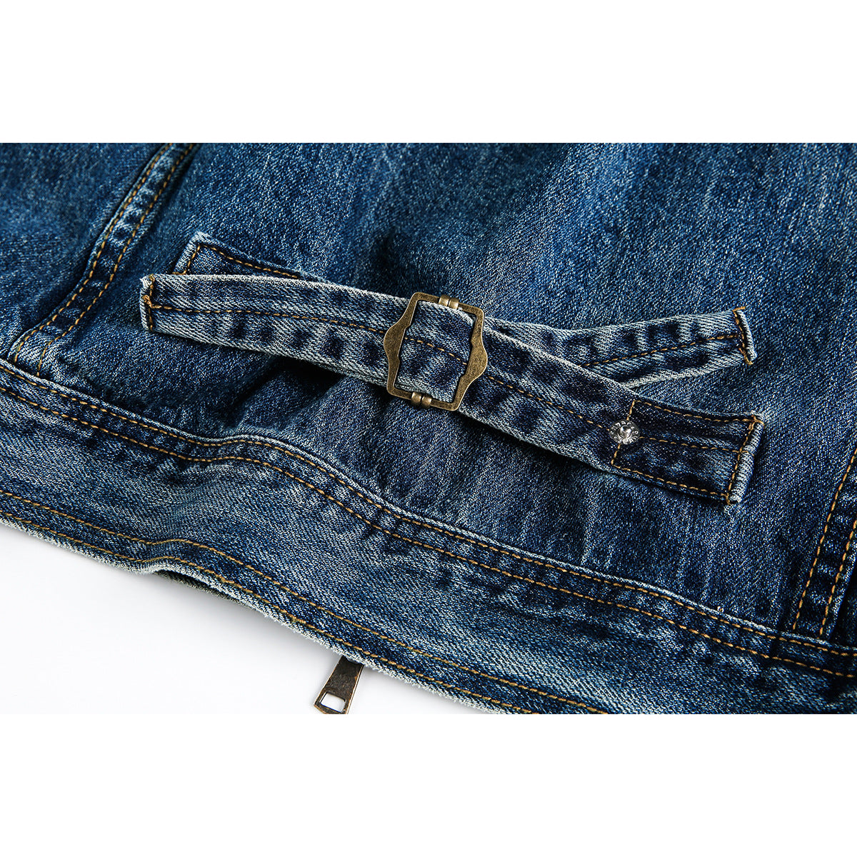 Close-up of a blue denim jacket hem with an adjustable strap and metal buckle.