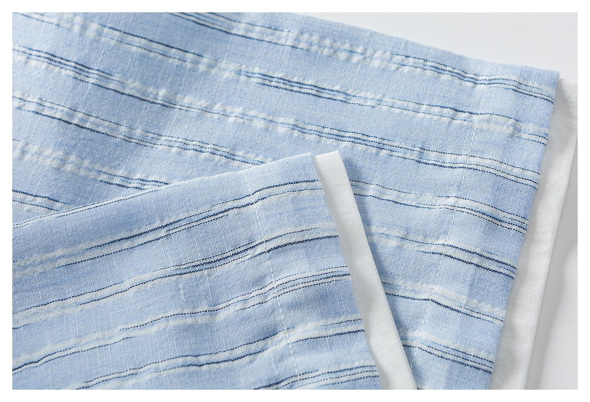 Close-up of a light blue striped shirt sleeve cuff with its folded edge and stitching.
