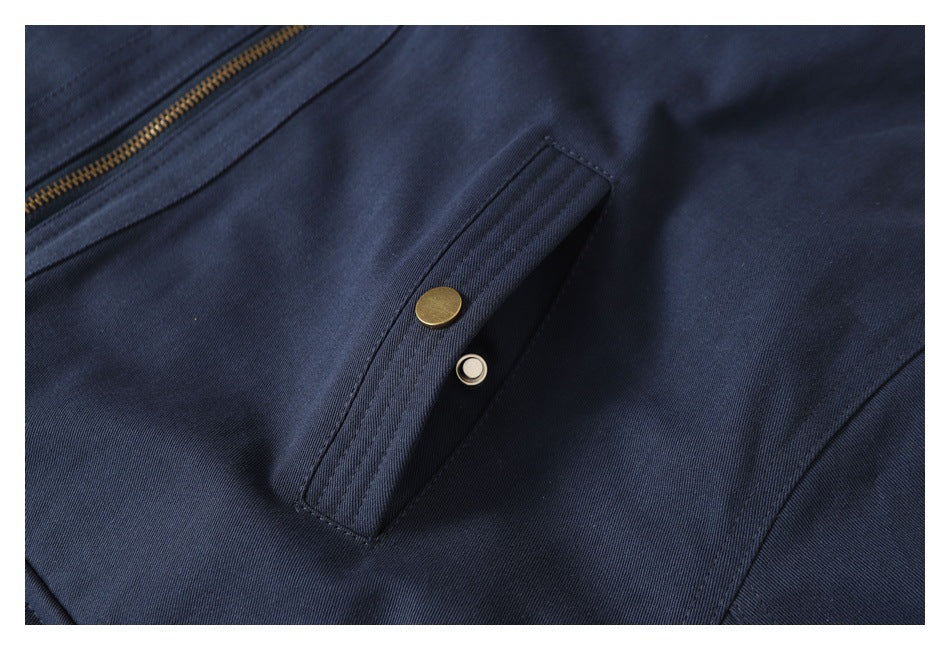Close-up of a navy garment's narrow snap-button pocket beside a brass-colored zipper.