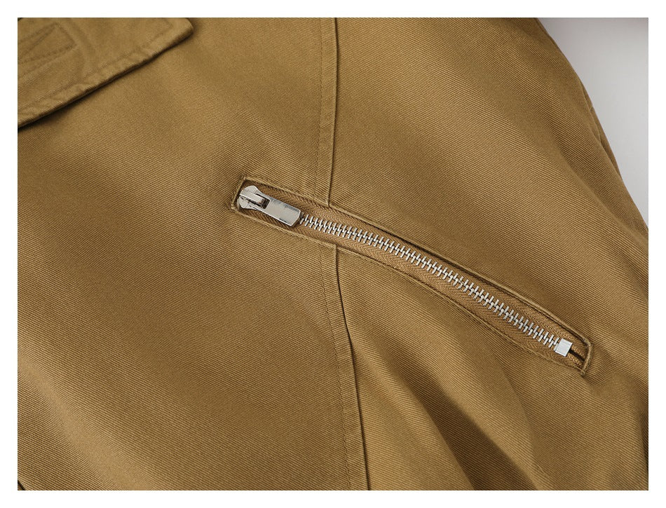 Close-up of a slanted silver zipper pocket on the tan jacket.