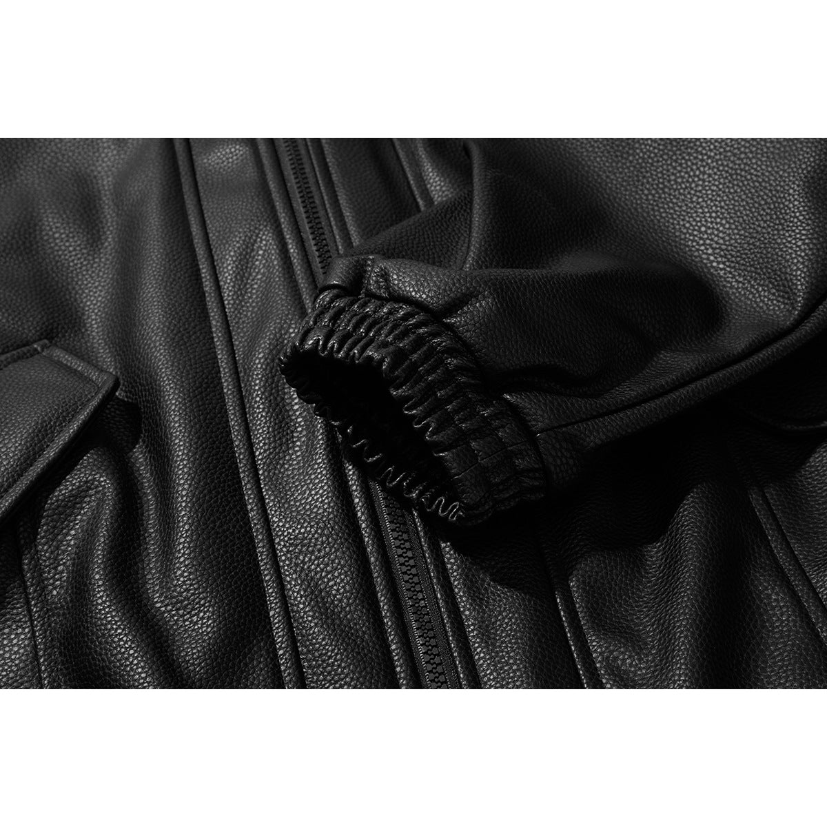 Close-up of a black jacket sleeve cuff with gathered stitching beside the front zipper.