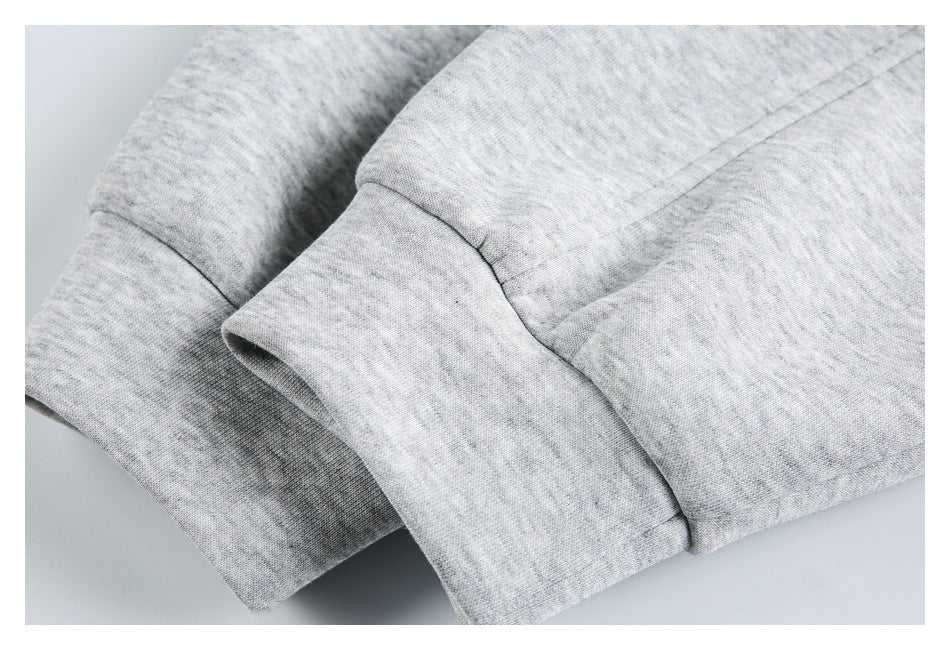 Close-up of light gray heather fabric with a wide stitched cuff or hem and ribbed edge.