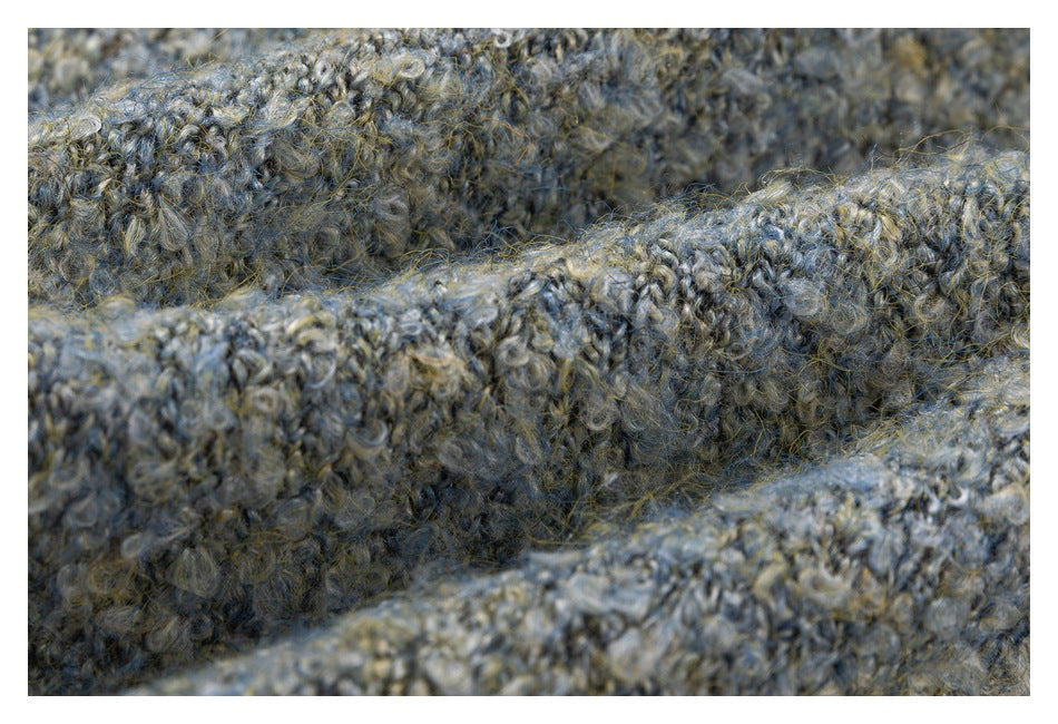 Macro view of thick, fuzzy gray-blue and beige knit folds and loops.