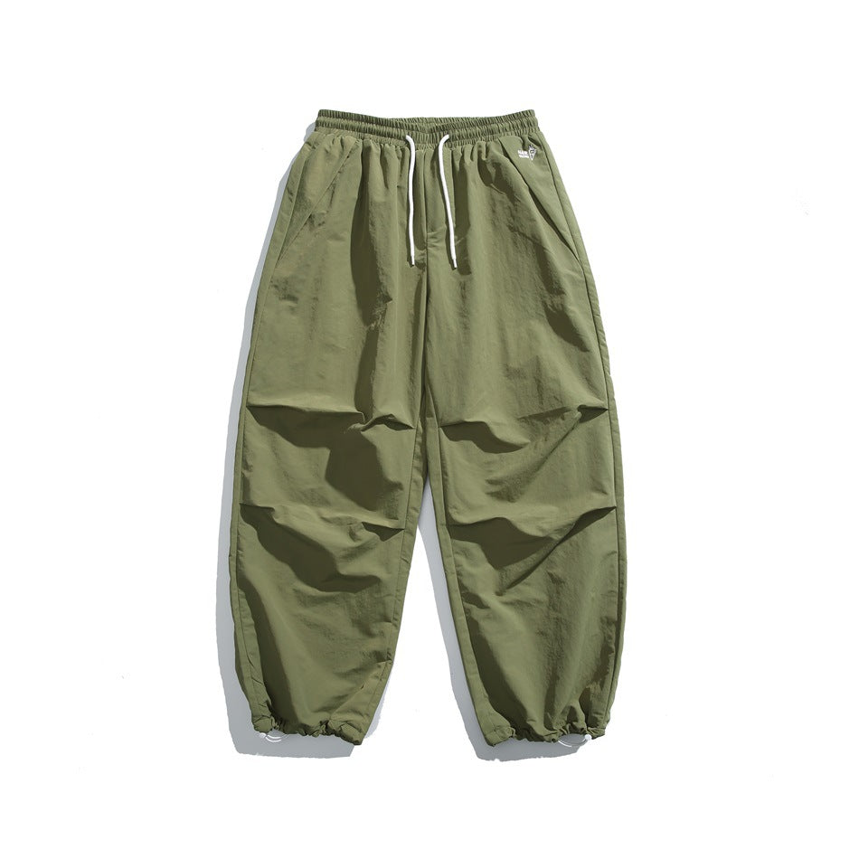 Green wide-leg drawstring pants with white cords, pleated knees and drawcord hems, flat lay