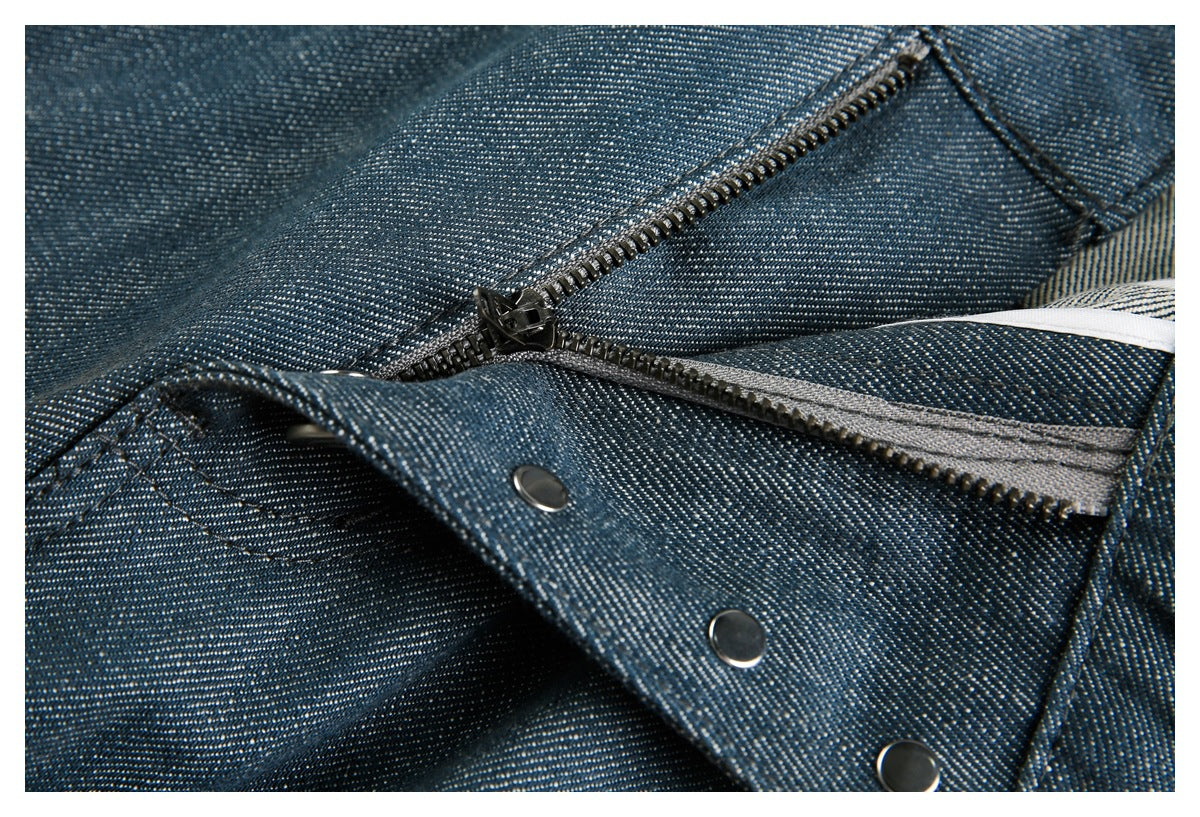 Close-up of a blue denim garment showing a metal zipper and snap fasteners.