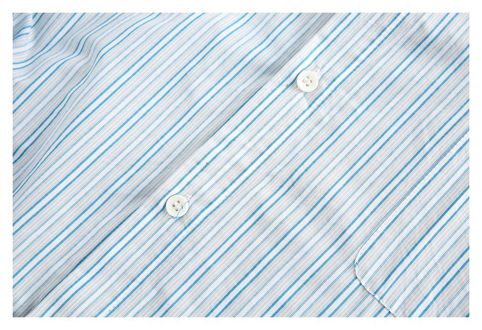 Close-up of a white shirt with thin blue and gray stripes, two white buttons, and part of a pocket.