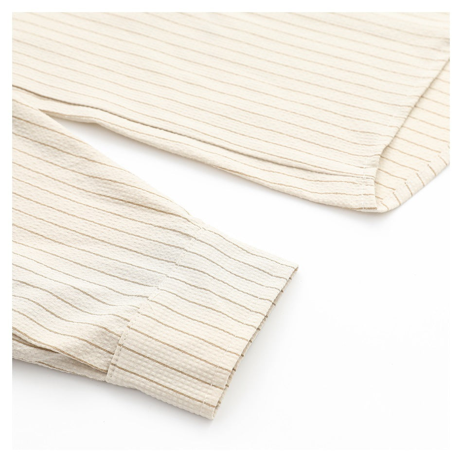 Close-up of the cream shirt's striped sleeve and buttoned cuff.