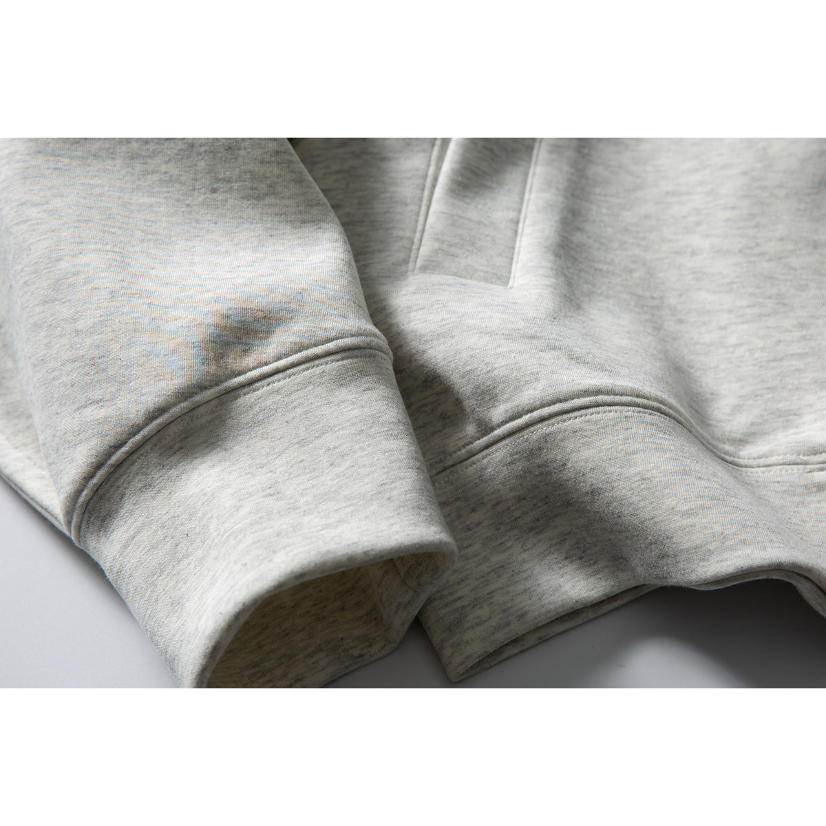 Close-up of the light gray heather sweatshirt's sleeve, ribbed cuff and hem.