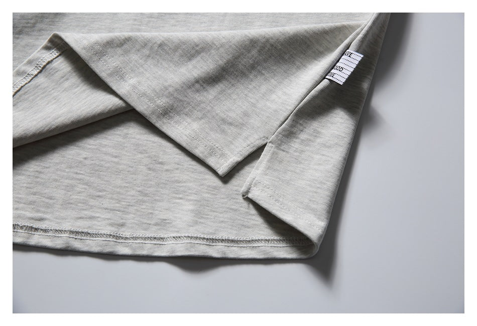 Close-up of the light gray T-shirt hem, stitching, and a small sewn side label.