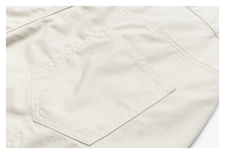 Close-up of an ivory trouser back patch pocket and surrounding stitching.